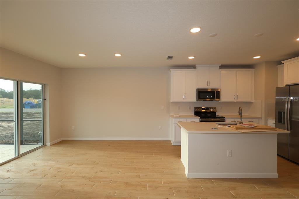 A kitchen with white cabinets, a center island, and light wood-look flooring — 6108 FELLOW WAGON WAY, ORLANDO, FL