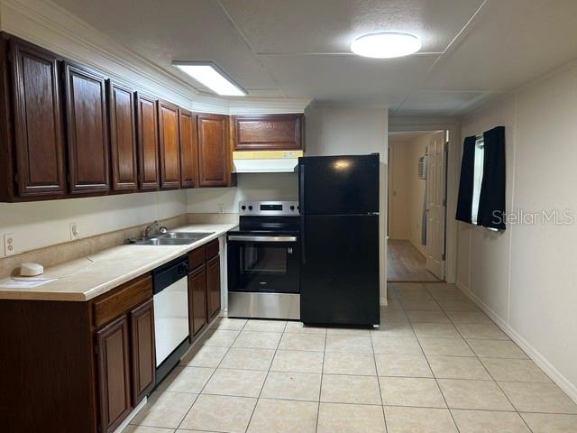 A kitchen features dark wood cabinets, stainless steel appliances, a black refrigerator, and tile flooring — 1481 NOCATEE STREET, INTERCESSION CITY, FL
