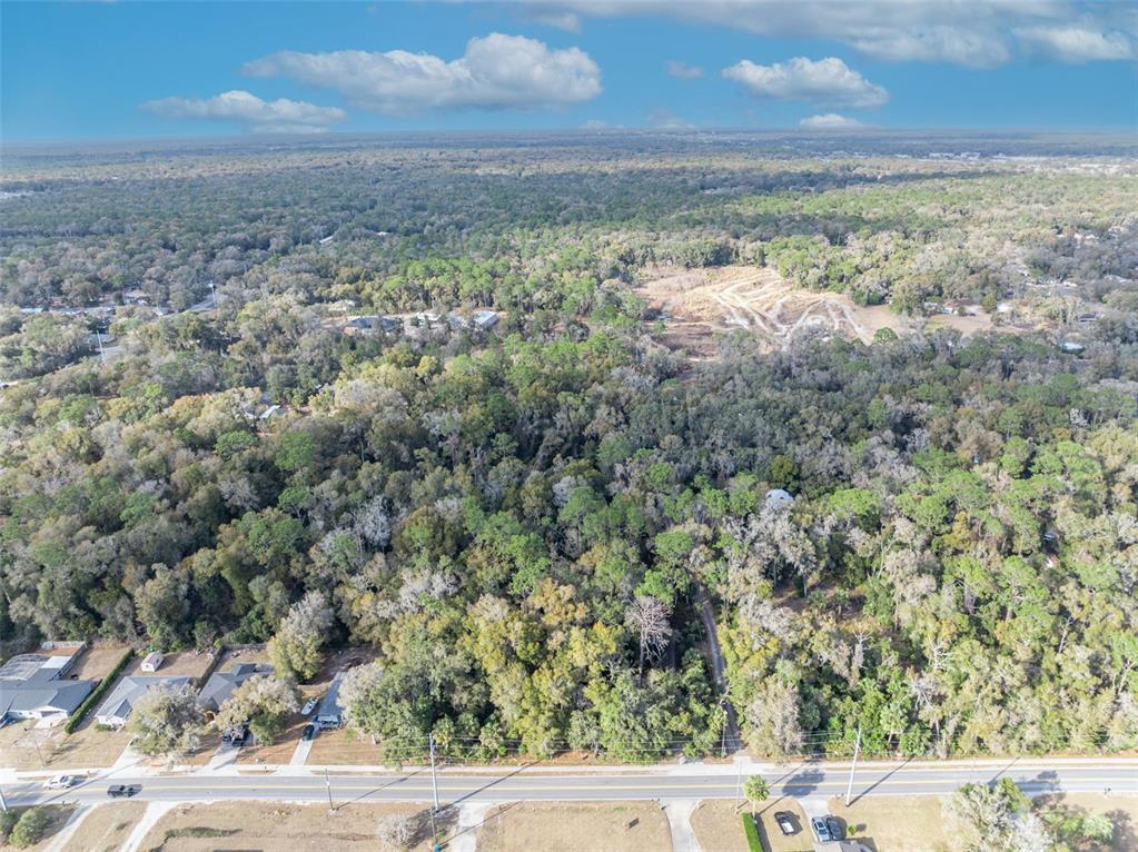 An aerial view shows a wooded lot situated between residential streets and a cleared area — W NEW YORK AVENUE, ORANGE CITY, FL