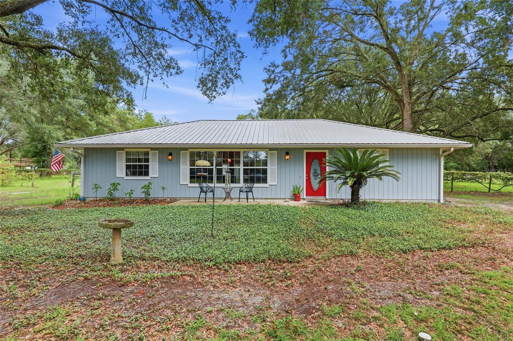 A single-story house with light blue siding, a metal roof, and a red front door — 753 SW MAPLETON STREET, FORT WHITE, FL