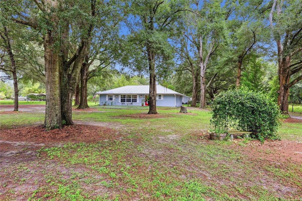 A light blue single-story house sits in a grassy yard surrounded by large oak trees — 753 SW MAPLETON STREET, FORT WHITE, FL