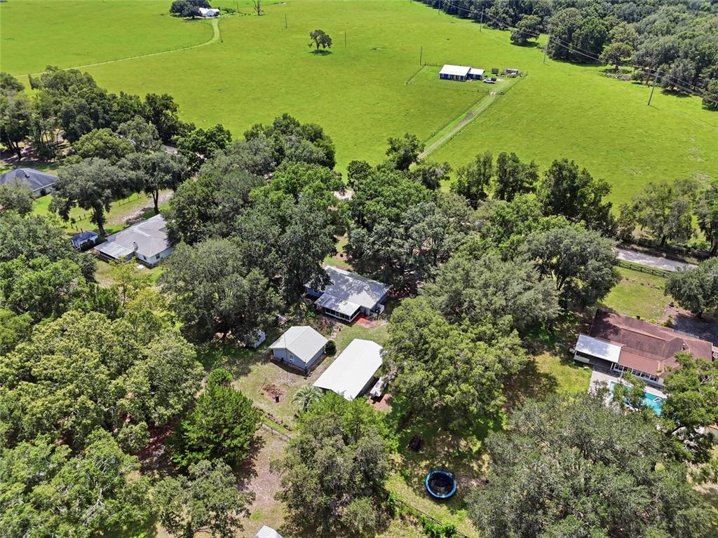 An aerial view shows several houses and outbuildings surrounded by trees and a large pasture — 753 SW MAPLETON STREET, FORT WHITE, FL