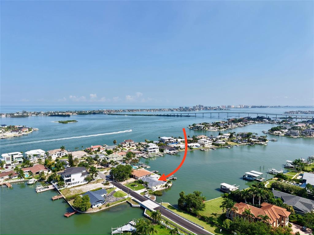An aerial view shows a waterfront house with a red arrow pointing to its roof — 902 OAKWOOD DRIVE, LARGO, FL