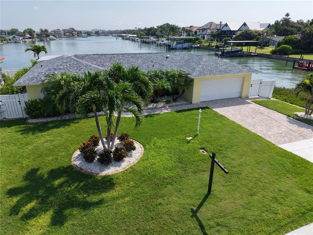 An aerial view shows a waterfront house with a shingled roof, garage, and palm trees — 902 OAKWOOD DRIVE, LARGO, FL