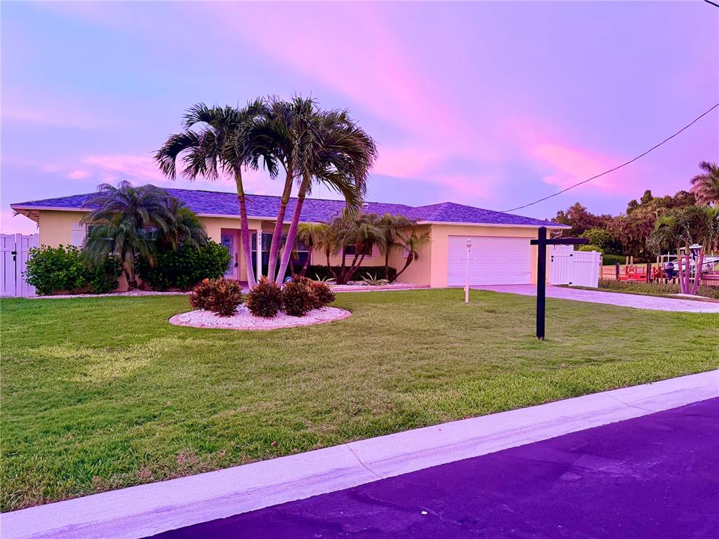 A single-story house with a palm tree-filled front yard under a vibrant purple sunset sky — 902 OAKWOOD DRIVE, LARGO, FL