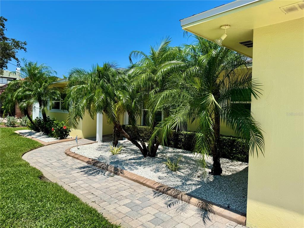 A paved walkway leads to the entrance of a yellow house with palm trees — 902 OAKWOOD DRIVE, LARGO, FL