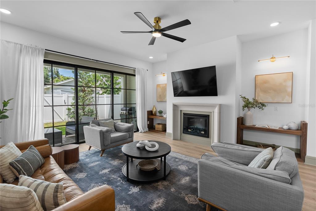 A living room features a fireplace, a mounted television, a ceiling fan, and sliding glass doors — 417 W ROSS AVENUE UNIT 2, TAMPA, FL