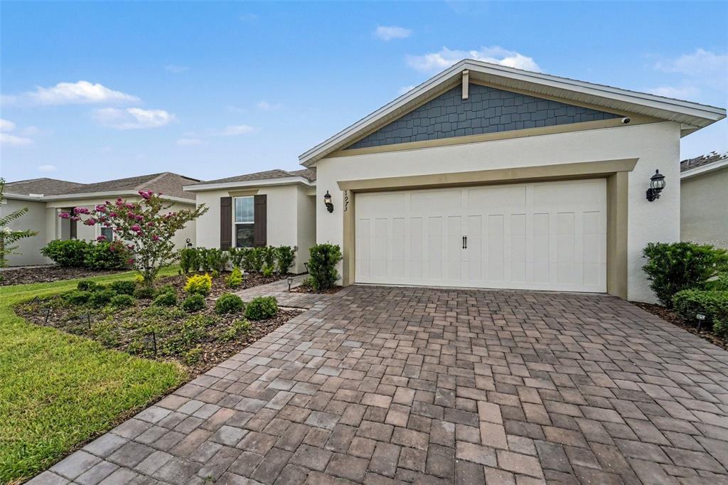 A single-story house features a white stucco exterior, a paver driveway, and a two-car garage — 1973 SPRING SHOWER CIRCLE, KISSIMMEE, FL