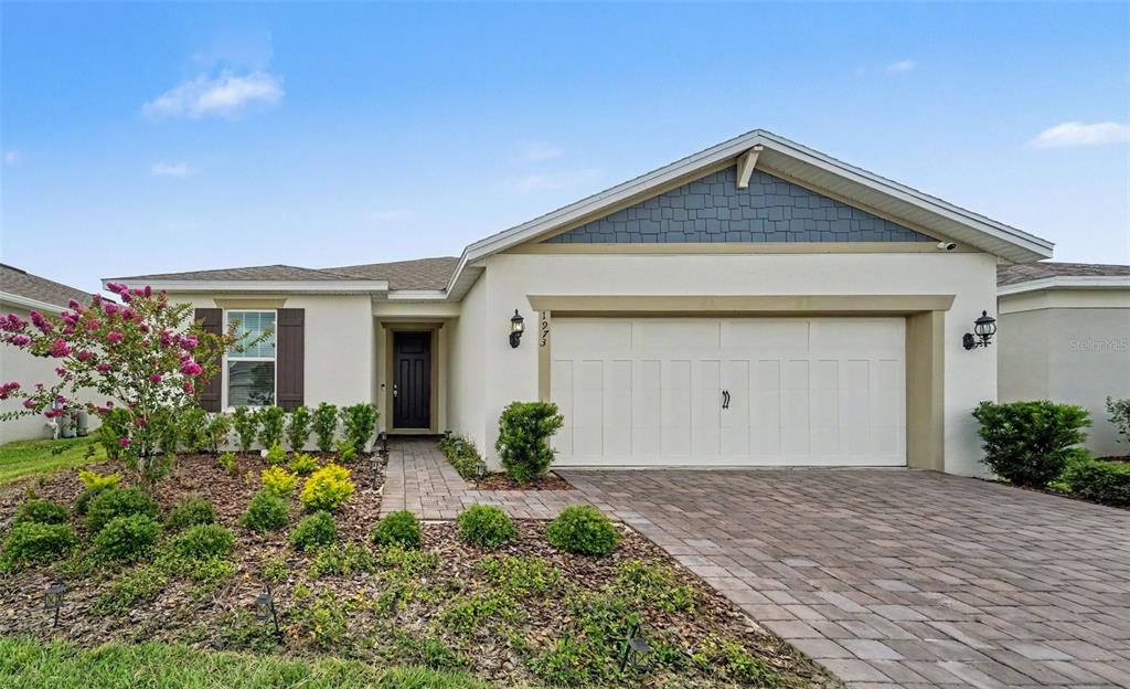 A single-story house with a white stucco exterior, a two-car garage, and a paved driveway — 1973 SPRING SHOWER CIRCLE, KISSIMMEE, FL