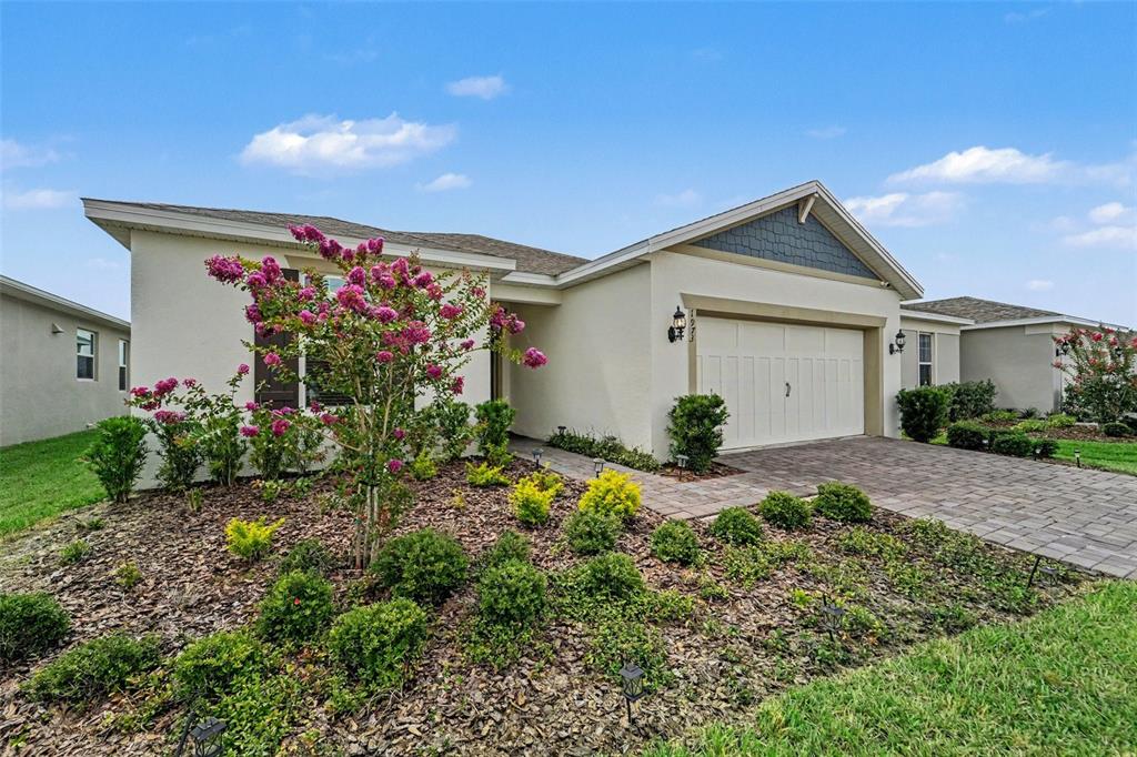 A single-story house with a white stucco exterior, a two-car garage, and a landscaped yard — 1973 SPRING SHOWER CIRCLE, KISSIMMEE, FL