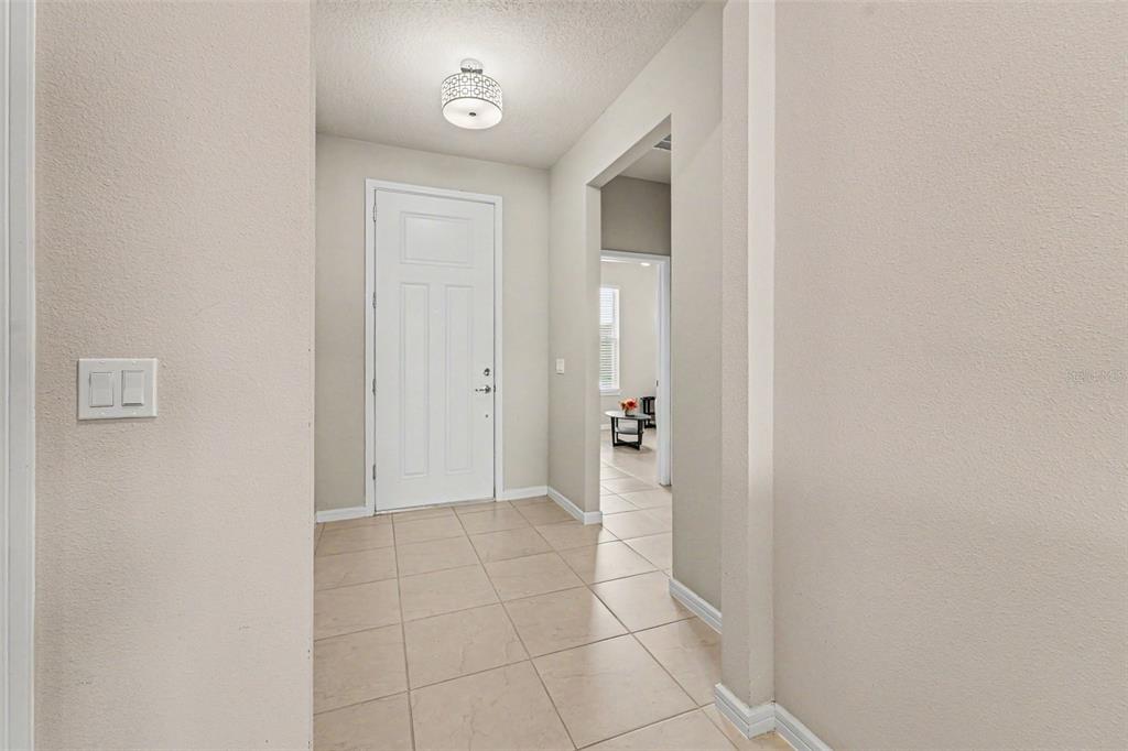 A tiled entryway features a white front door, neutral walls, and a ceiling light fixture — 1973 SPRING SHOWER CIRCLE, KISSIMMEE, FL