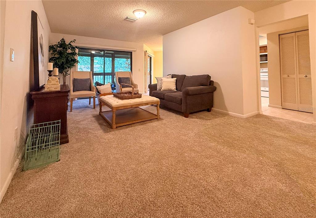 A carpeted living room features a sofa, two armchairs, a coffee table, and a sliding door — 46 HEMBURY LANE UNIT 46, PALM COAST, FL
