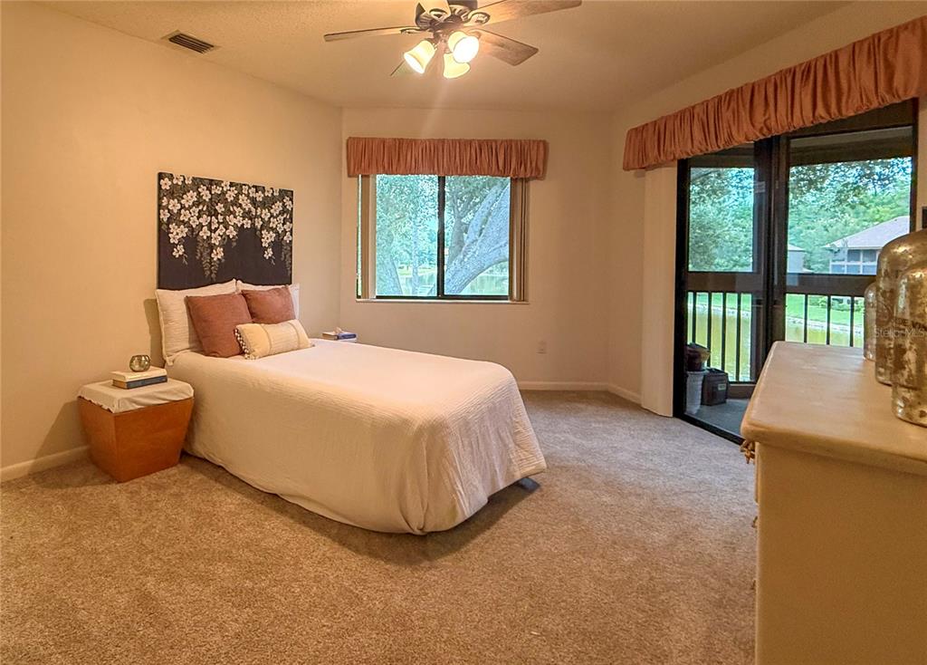 A bedroom features a single bed, carpeted flooring, a ceiling fan, and sliding glass doors — 46 HEMBURY LANE UNIT 46, PALM COAST, FL