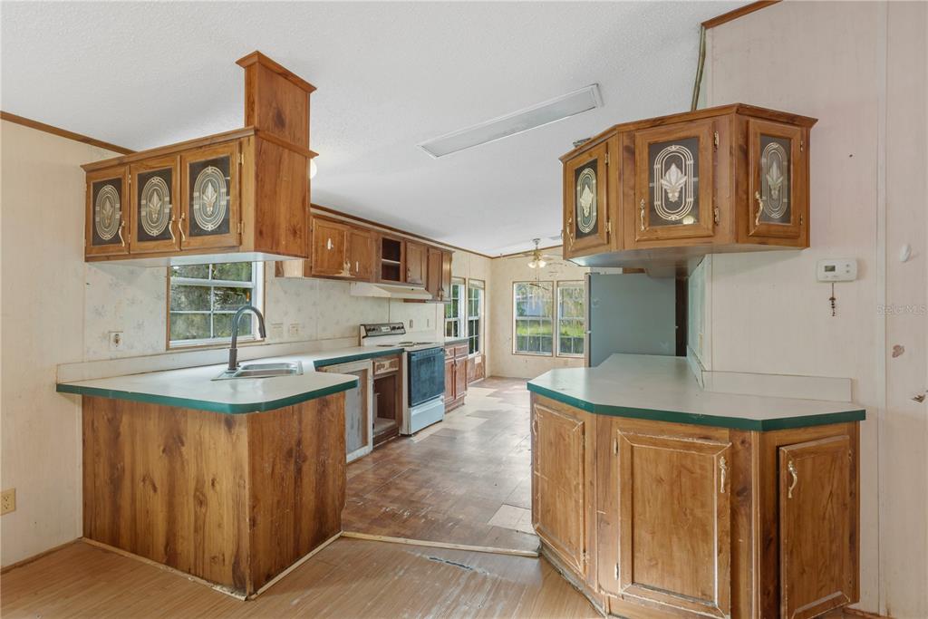 A kitchen with wood cabinets, green laminate countertops, and light-colored wood-paneled walls — 11620 E BAY ROAD, GIBSONTON, FL