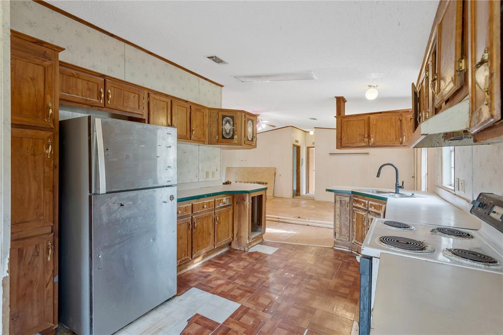 A kitchen with wood cabinets, a stainless steel refrigerator, and a white electric stove — 11620 E BAY ROAD, GIBSONTON, FL