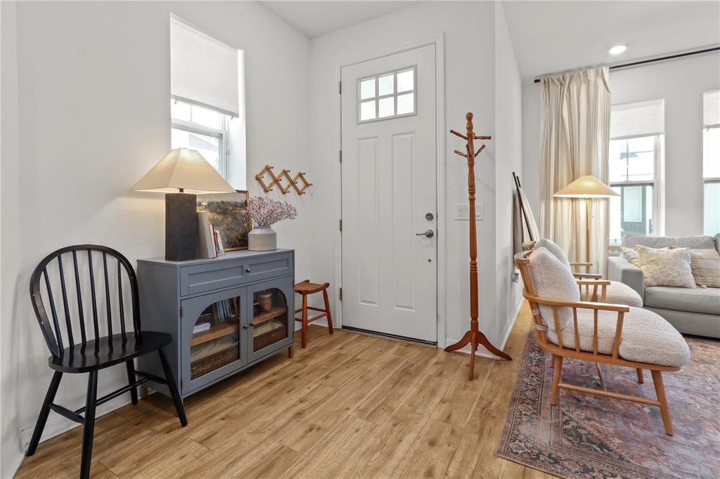 A bright entryway features a blue cabinet, a black chair, and a wooden coat rack — 923 COLIE ALLEY, WINTER GARDEN, FL