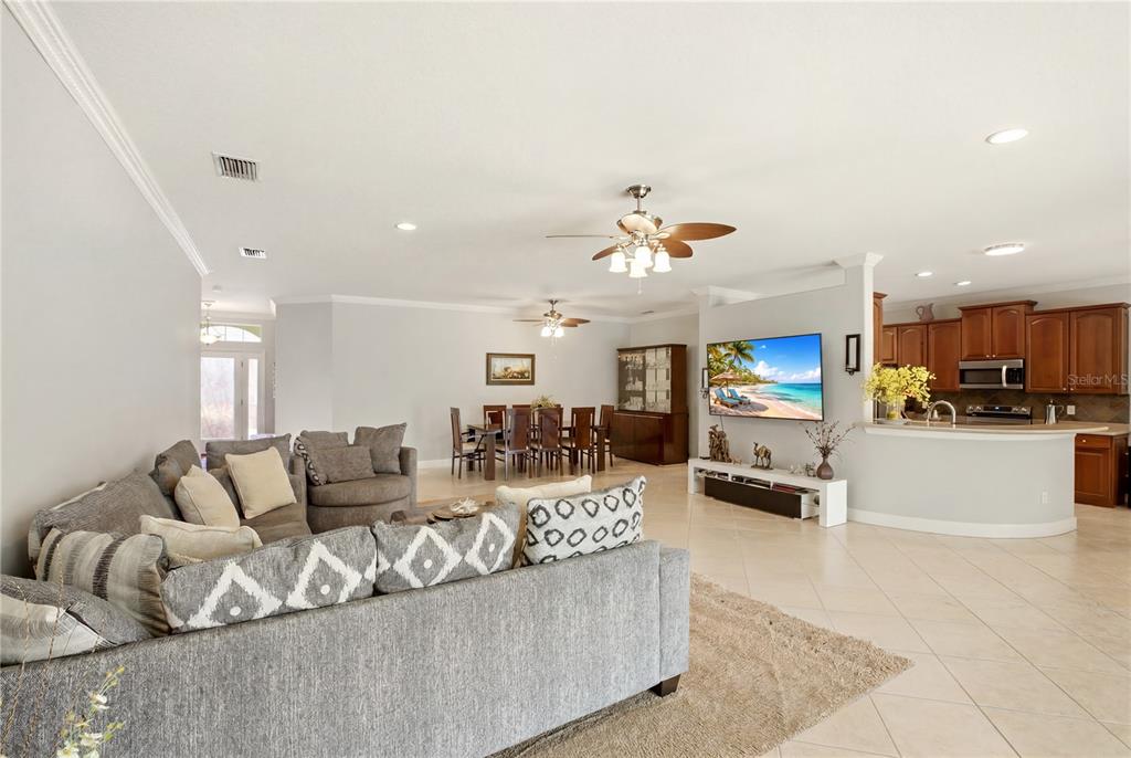 An open-concept living room and kitchen with tile flooring, a sectional sofa, and a television — 7131 67TH TER E, BRADENTON, FL