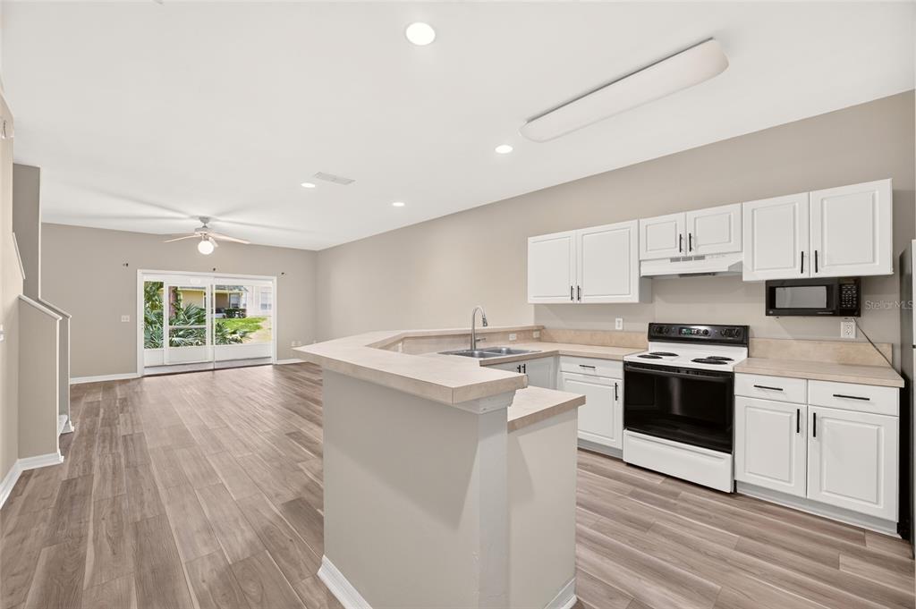 A kitchen with white cabinets and a breakfast bar opens to a living area — 13200 W NEWBERRY ROAD UNIT HH199, NEWBERRY, FL