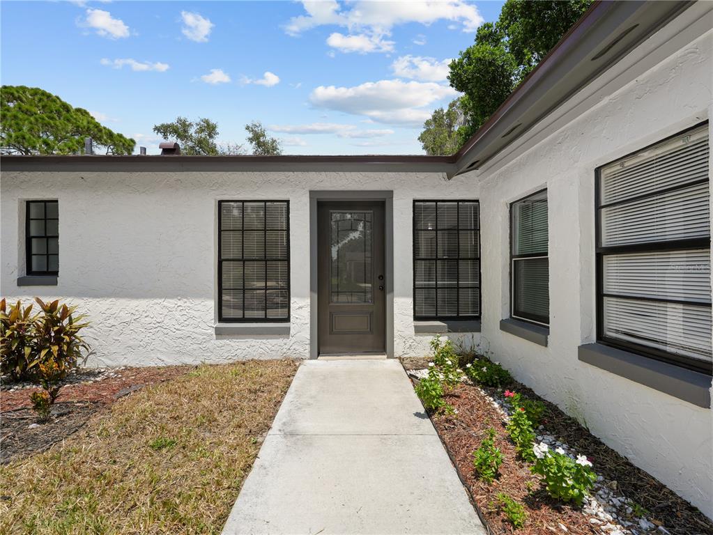 A white stucco house exterior features a dark front door, black-framed windows, and a walkway — 2181 LINDEN ROAD, WINTER PARK, FL
