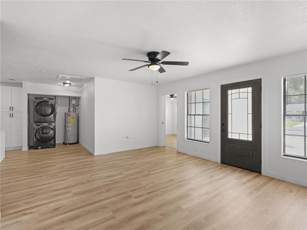 A room with light wood-look flooring, a ceiling fan, a laundry area, and a door — 2181 LINDEN ROAD, WINTER PARK, FL