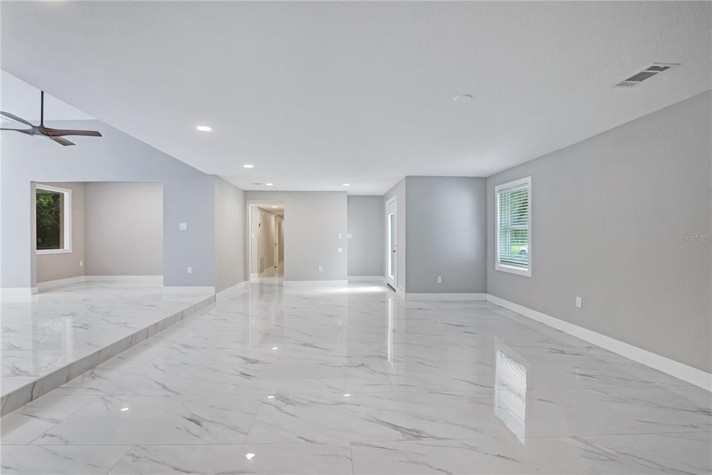 A spacious living area features white marble-look tile flooring, light gray walls, and recessed lighting — 2317 FARMWOOD CIRCLE, GOTHA, FL