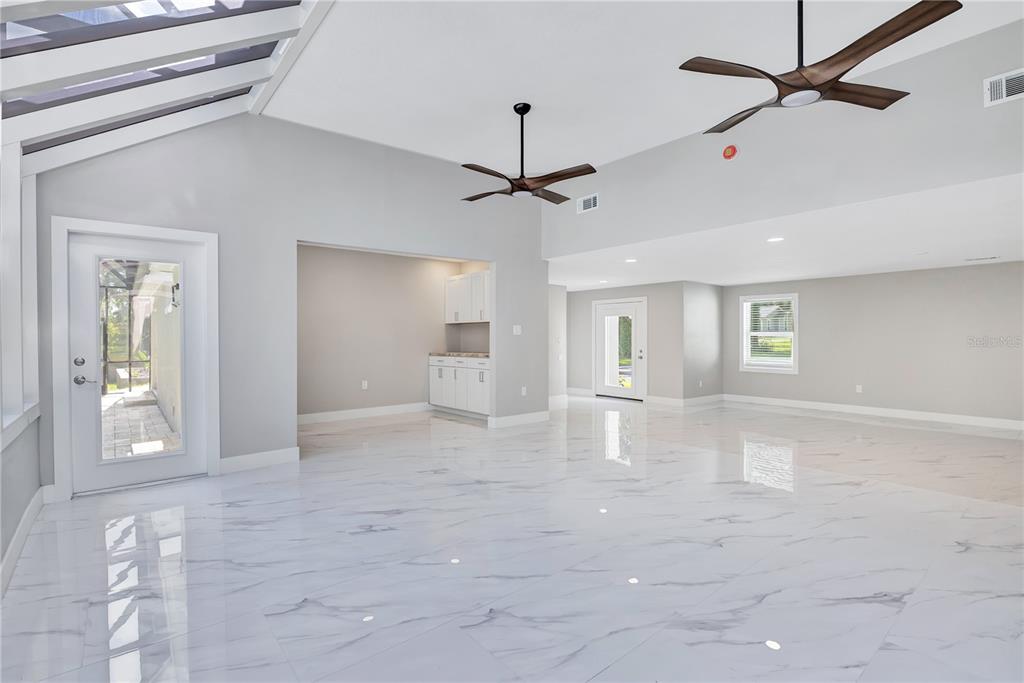 A spacious room features white marble-look tile flooring, two ceiling fans, and a wet bar — 2317 FARMWOOD CIRCLE, GOTHA, FL