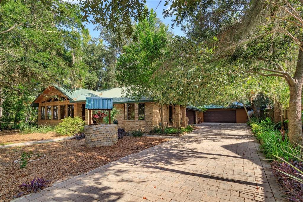 A brick house with a green metal roof, a stone wishing well, and a paved driveway — 10350 LAKE LOUISA ROAD, CLERMONT, FL