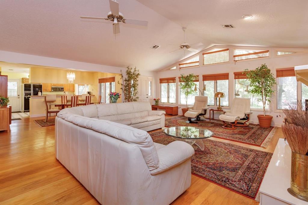 A spacious living room with a white sectional sofa, hardwood floors, and large windows — 10350 LAKE LOUISA ROAD, CLERMONT, FL