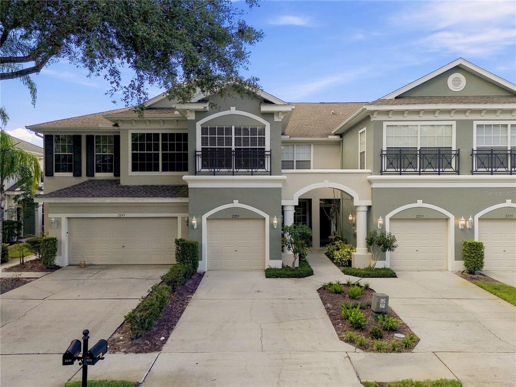 A two-story townhouse exterior features four garage doors, balconies, and a shared arched entryway — 2251 PARK CRESCENT DRIVE, LAND O LAKES, FL