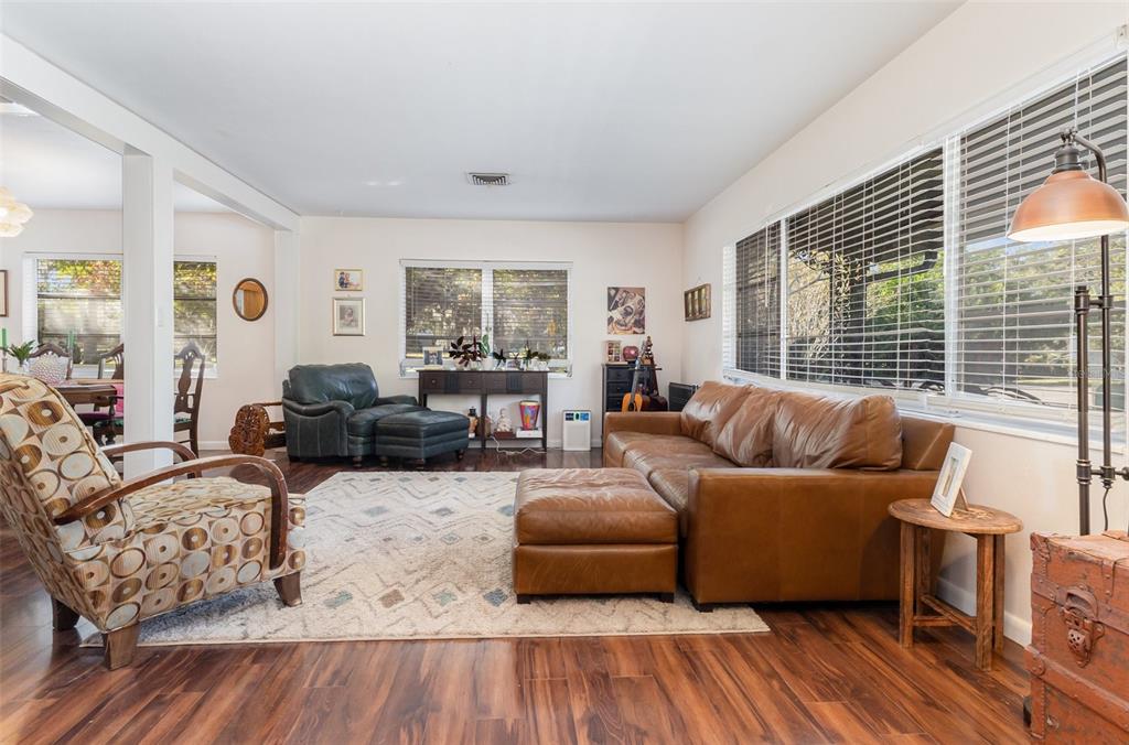 A living room features wood-look flooring, a brown leather sofa, and a patterned armchair — 29 GOLF VIEW CIRCLE NE, WINTER HAVEN, FL