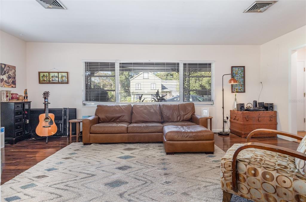 A living room features a brown leather sectional, a patterned area rug, and a guitar — 29 GOLF VIEW CIRCLE NE, WINTER HAVEN, FL