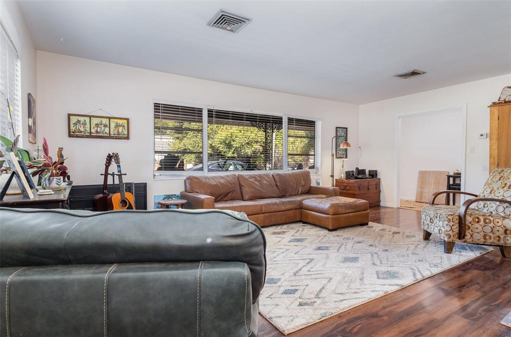 A living room features a leather sectional, a patterned armchair, and a large area rug — 29 GOLF VIEW CIRCLE NE, WINTER HAVEN, FL