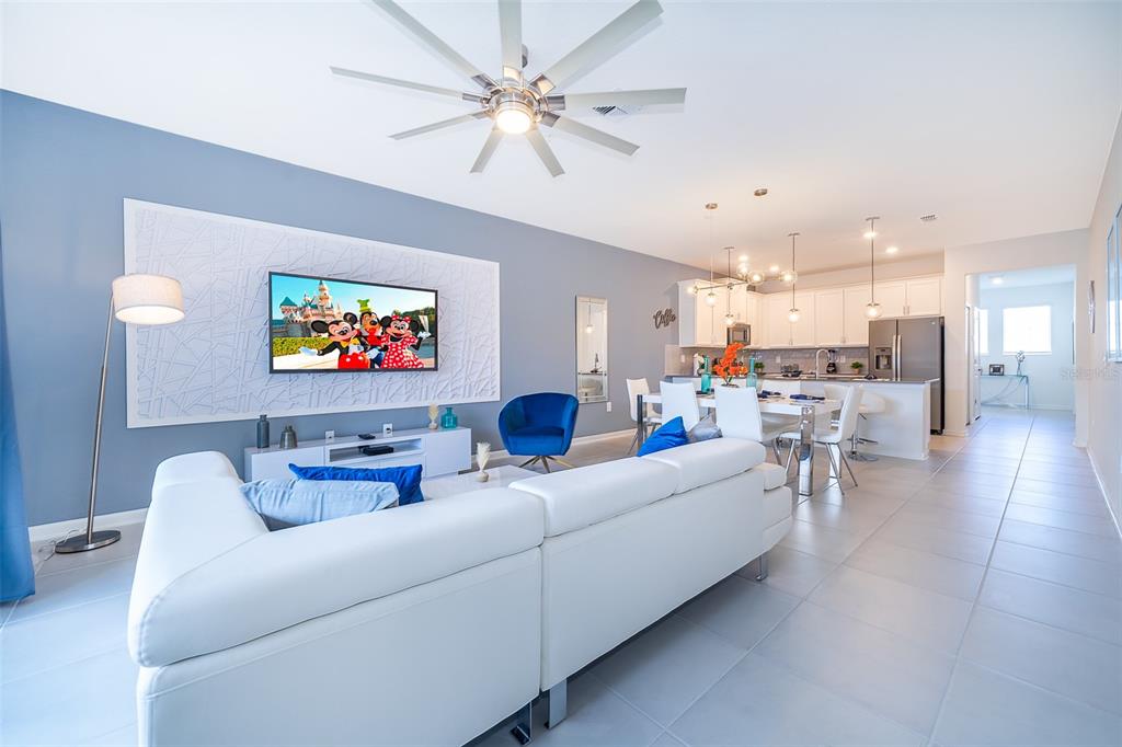 A modern open-concept living and dining area features a white sectional sofa and tiled floors — 8875 CABOT CLIFFS DRIVE UNIT 103, DAVENPORT, FL