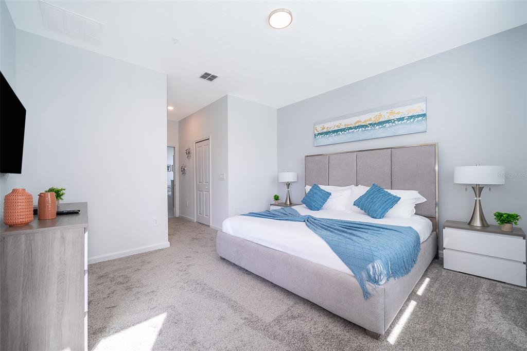 A bedroom features a gray upholstered bed, blue accents, and a dresser on carpeted flooring — 8875 CABOT CLIFFS DRIVE UNIT 103, DAVENPORT, FL