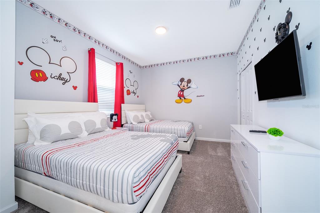 A bedroom features two beds, Mickey Mouse wall decals, and a white dresser with a television — 8875 CABOT CLIFFS DRIVE UNIT 103, DAVENPORT, FL
