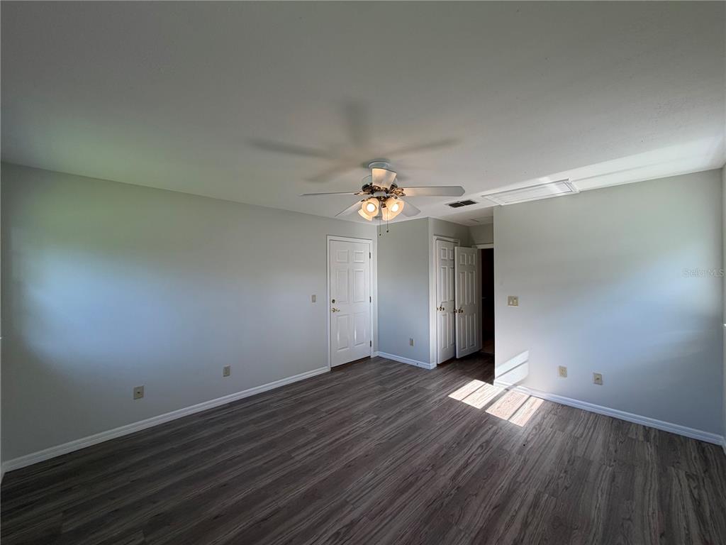 An empty room features light gray walls, dark wood-look flooring, and a ceiling fan — 1305 W SPENCER STREET, PLANT CITY, FL