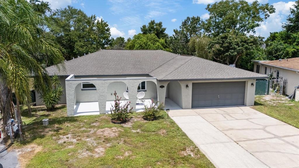 A single-story house with a gray roof, stucco exterior, arched front porch, and two-car garage — 5865 TERN DRIVE, NEW PORT RICHEY, FL