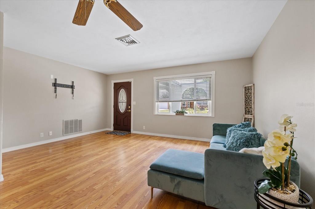 A living room features hardwood floors, a teal sectional sofa, and a brown front door — 5865 TERN DRIVE, NEW PORT RICHEY, FL