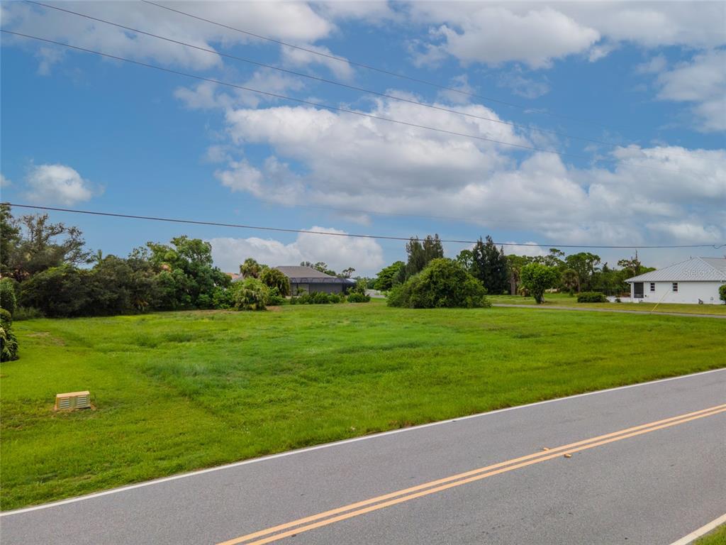 An aerial view shows a vacant grassy lot situated between a house and a road — 4200 CAPE HAZE DRIVE, PLACIDA, FL