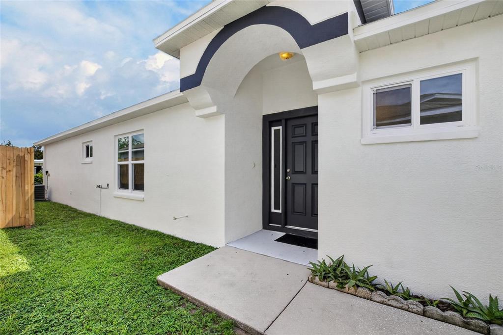 A white house exterior features a dark front door, arched entryway, and a concrete walkway — 535 SCARLET MAPLE COURT, PLANT CITY, FL