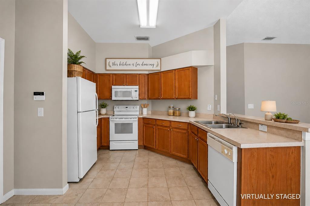A kitchen with wood cabinets, white appliances, and a beige countertop in a tiled room — 535 SCARLET MAPLE COURT, PLANT CITY, FL