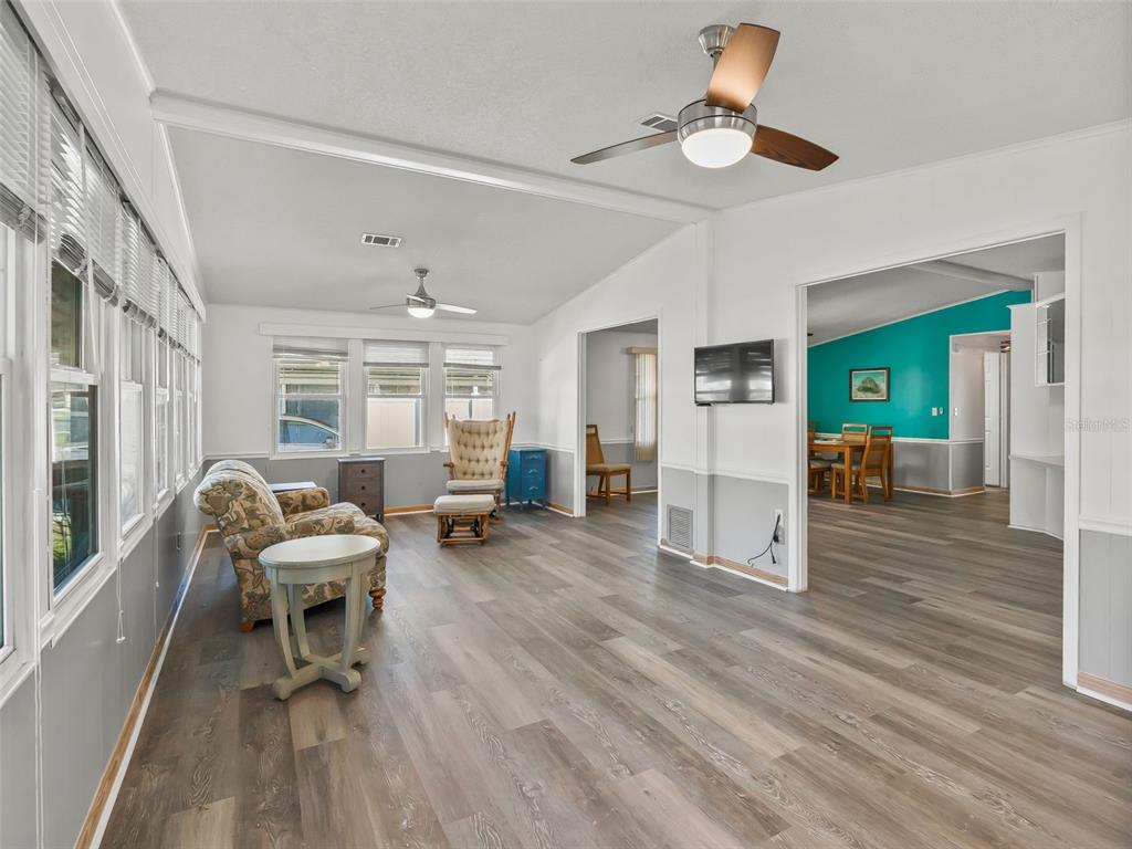 A living room with wood-look flooring, a ceiling fan, and a view into a dining area — 1514 HILLCREST DRIVE, LADY LAKE, FL