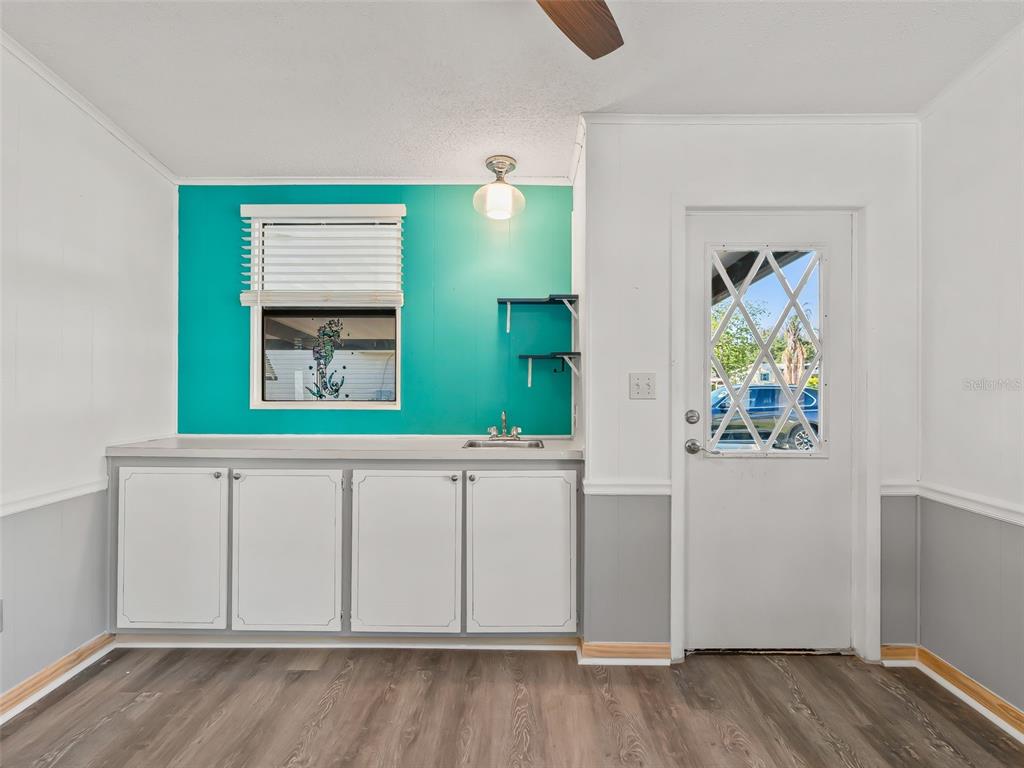 A room features a teal accent wall, white cabinets, a small sink, and a door — 1514 HILLCREST DRIVE, LADY LAKE, FL