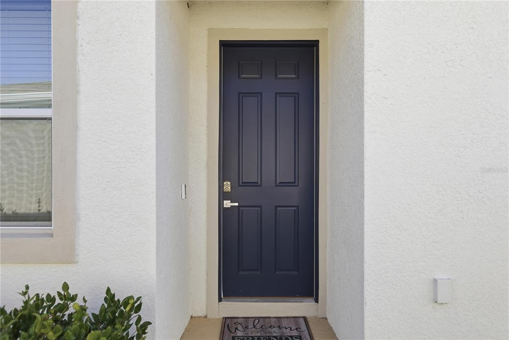 A dark blue front door with a welcome mat is set in a white wall — 5341 NW 48TH PLACE, OCALA, FL