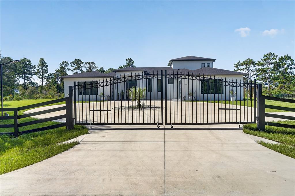 A modern house with a concrete driveway and a black metal gate in the foreground — 20722 QUINELLA STREET, ORLANDO, FL
