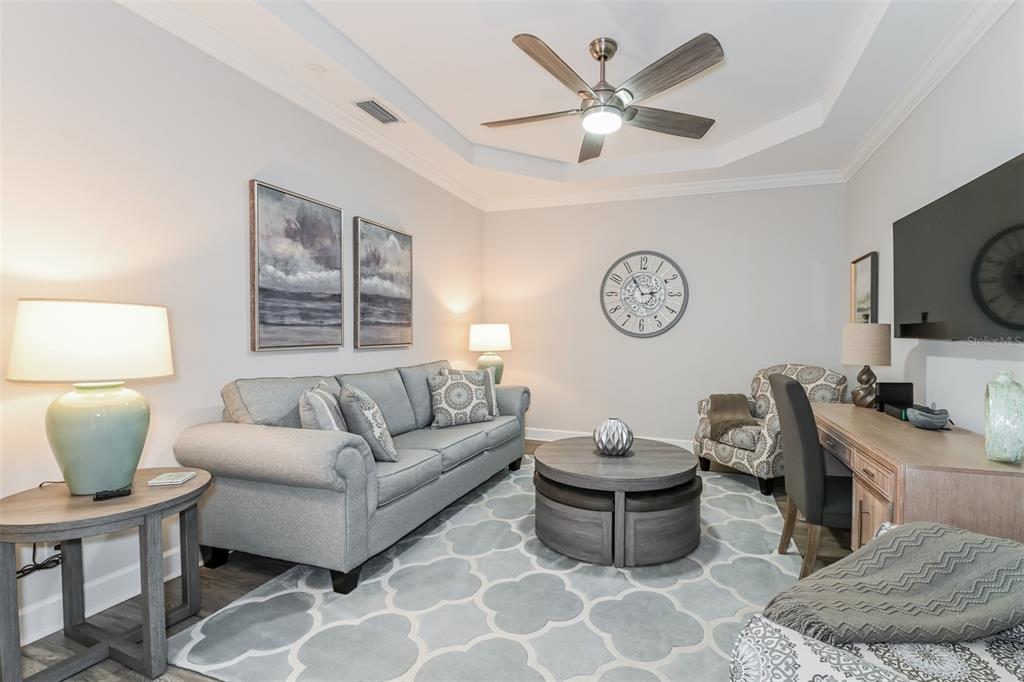 A living room features a gray sofa, a round coffee table, and a desk area — 9636 MONTELANICO LOOP UNIT 101, NAPLES, FL