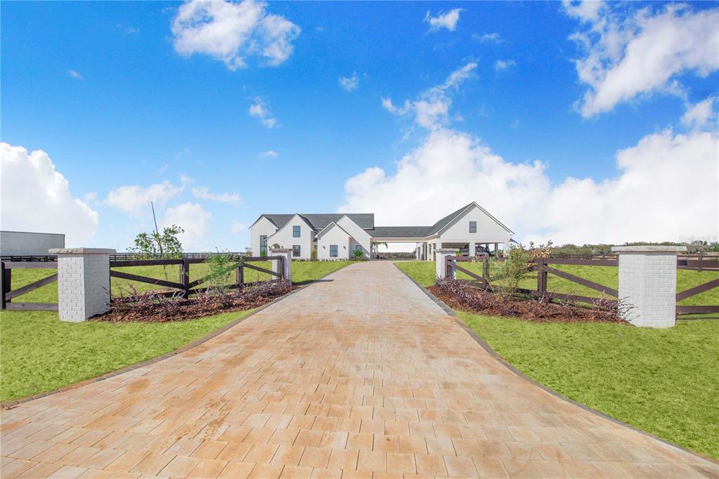 A long paver driveway leads to a white farmhouse with a covered breezeway — 1109 MINUTE MANN ROAD, FROSTPROOF, FL