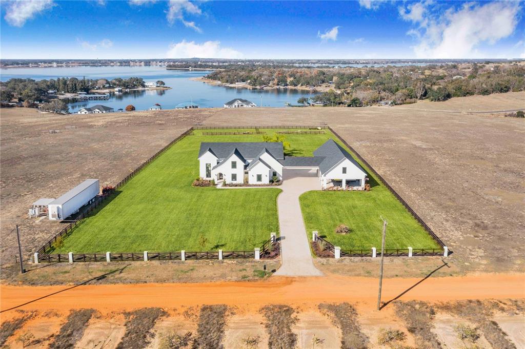 An aerial view shows a white house with a dark roof on a fenced lot — 1109 MINUTE MANN ROAD, FROSTPROOF, FL