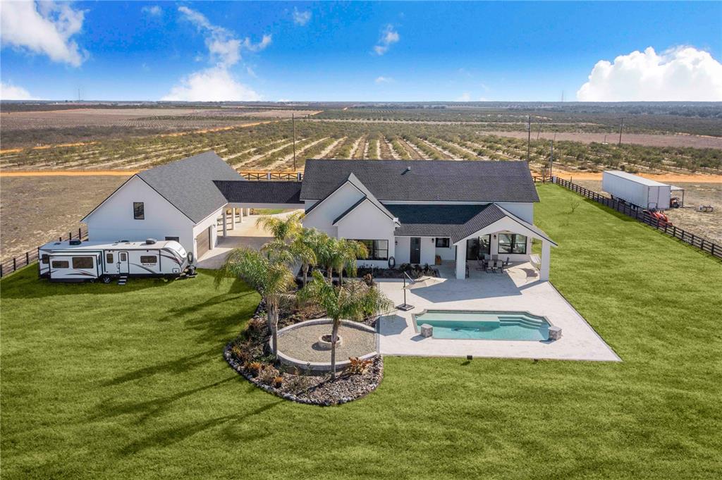 An aerial view of a white house with a pool, patio, and attached garage — 1109 MINUTE MANN ROAD, FROSTPROOF, FL
