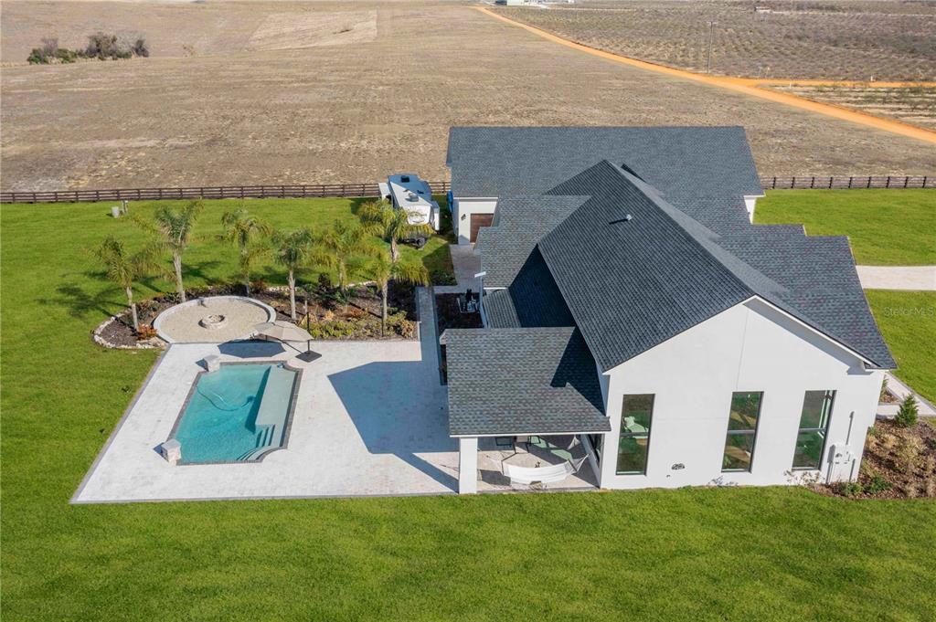 An aerial view of a modern white house with a pool, patio, and palm trees — 1109 MINUTE MANN ROAD, FROSTPROOF, FL
